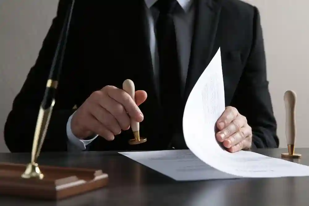 A professional in a formal black suit using a traditional wooden hand stamp to notarize a document