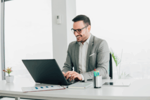 professional male executive in a grey suit and glasses smiling while working